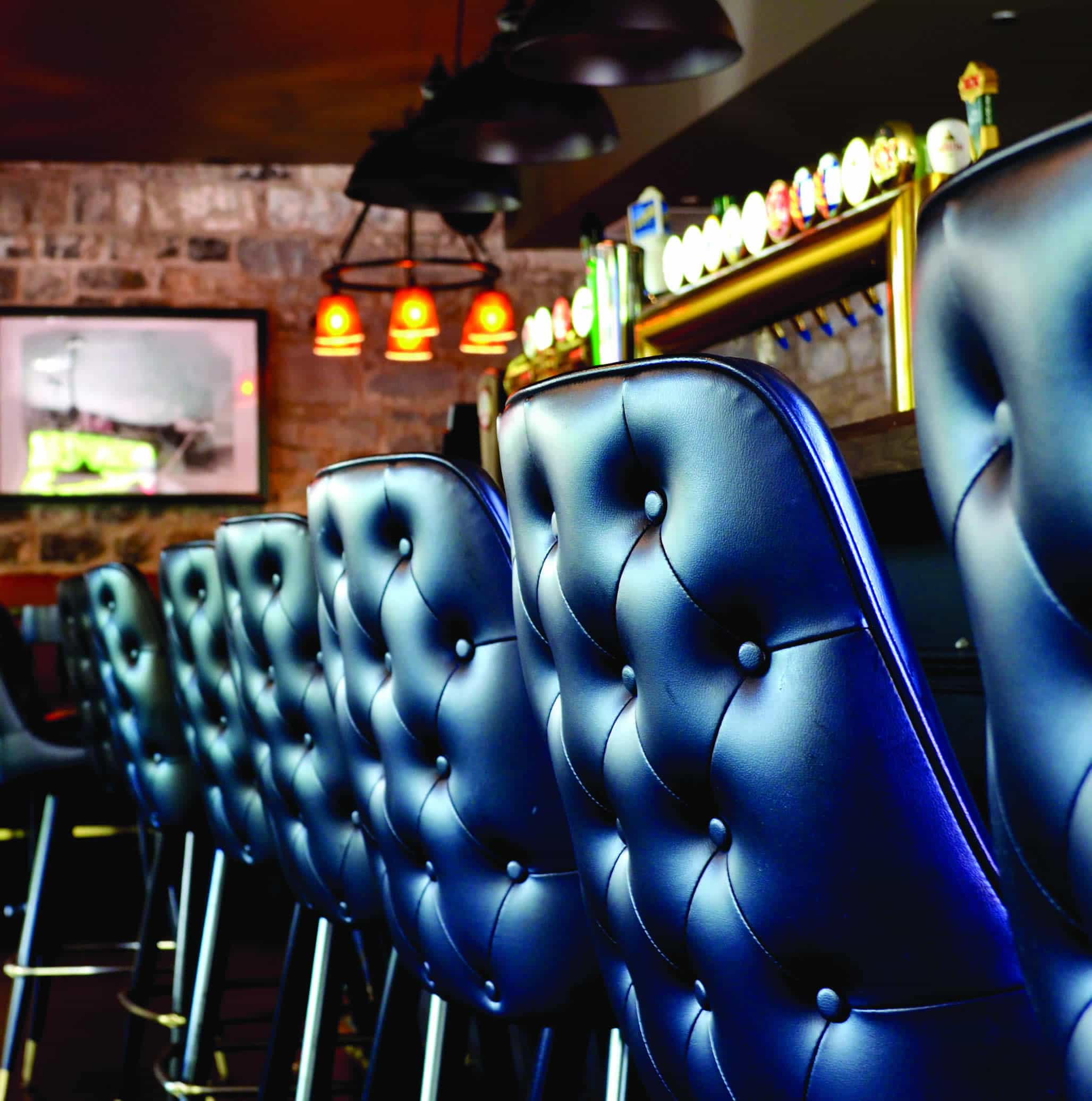Une rangée de tabourets de bar en cuir bleu capitonné